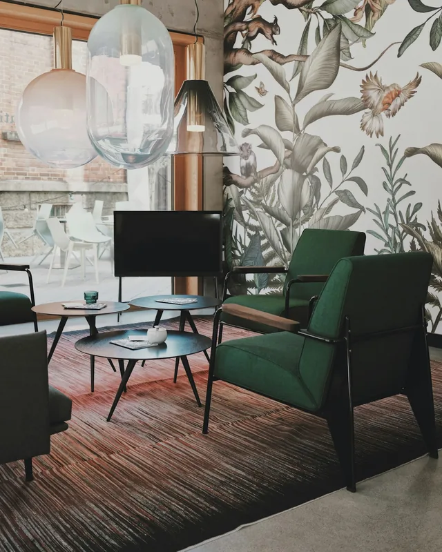 Botanical wallpaper mural behind green lounge chairs
